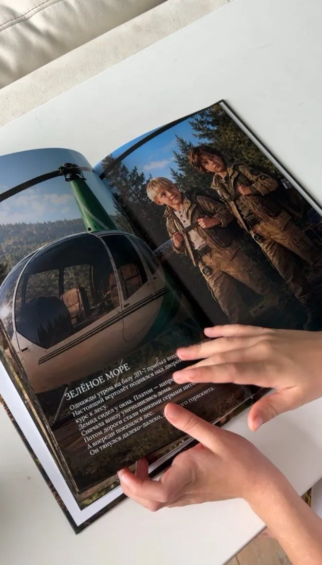 Разворот книги с главой «Зелёное море» в детских руках